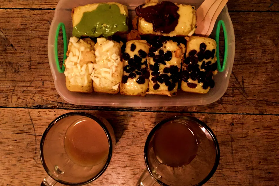 Kue balok di piring dengan dua cangkir berisi bandrek dan bajigur