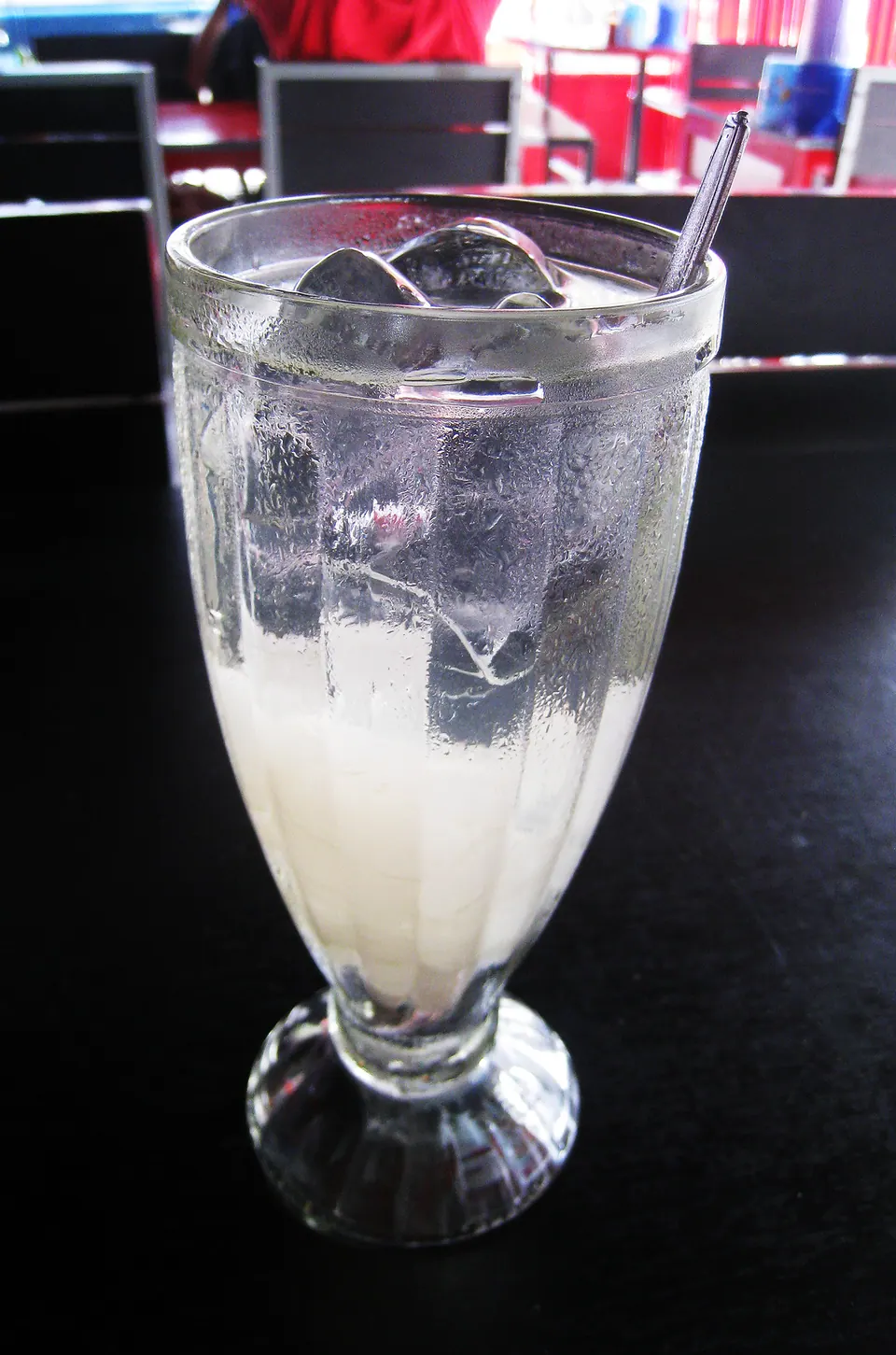 Segelas es lidah buaya dengan potongan daging lidah buaya bening dalam sirup dan es batu