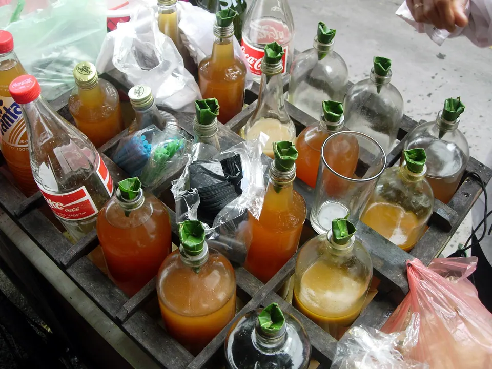 Botol-botol berisi jamu berwarna oranye, kuning, dan hijau berjajar