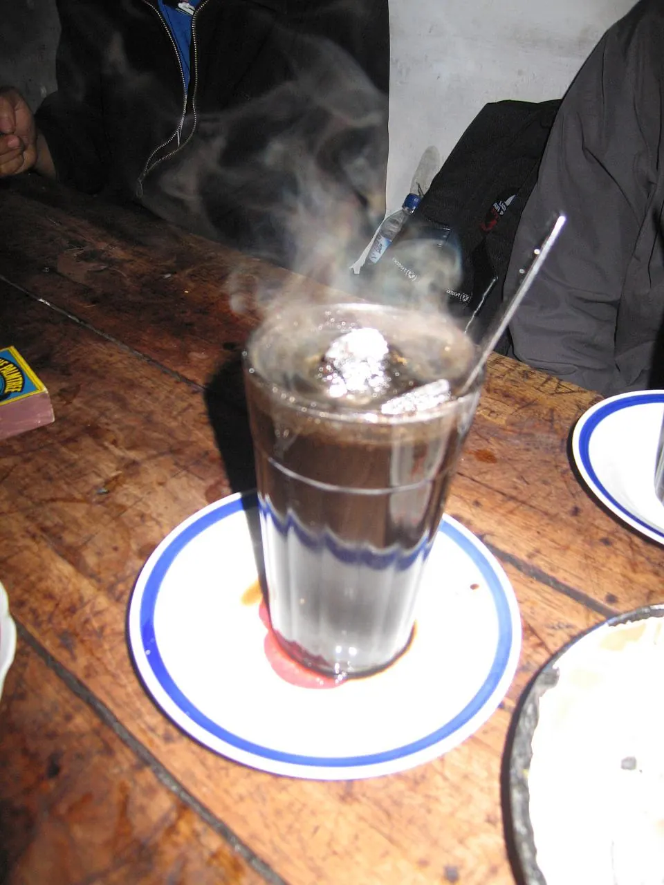 Segelas kopi joss dengan bongkahan arang di dalamnya di angkringan Lik Man, Yogyakarta