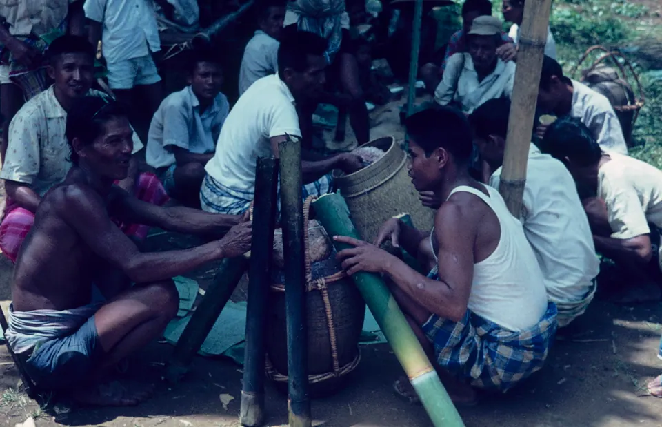 Laki-laki Toraja minum tuak dari bumbung bambu di sebuah pesta pernikahan, foto arsip 1960-an