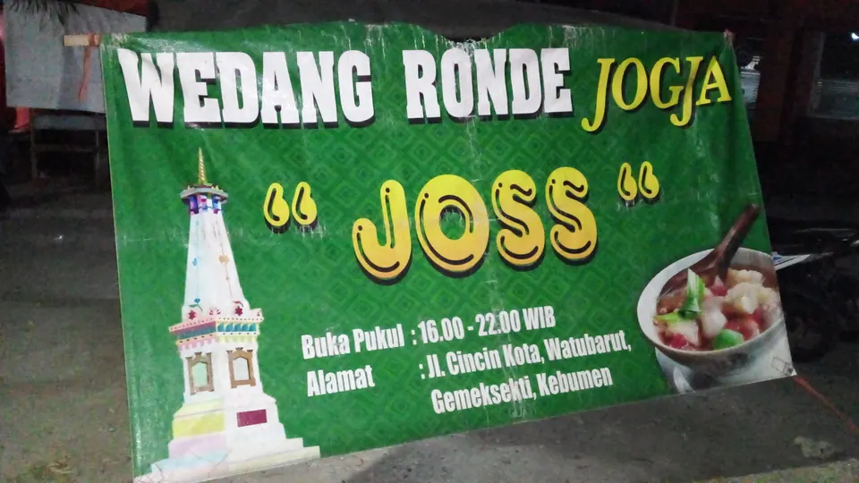 Pedagang wedang ronde dengan gerobak dan panci kuah jahe di malam hari